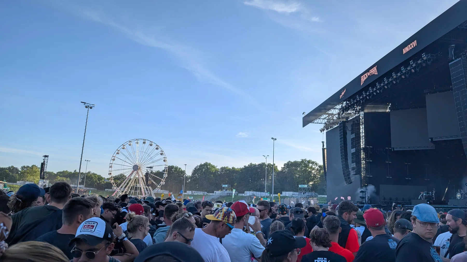 Blick aus der Menge auf die Hauptbühne von Rock im Park 2026, links das Riesenrad, strahlend blauer Himmel